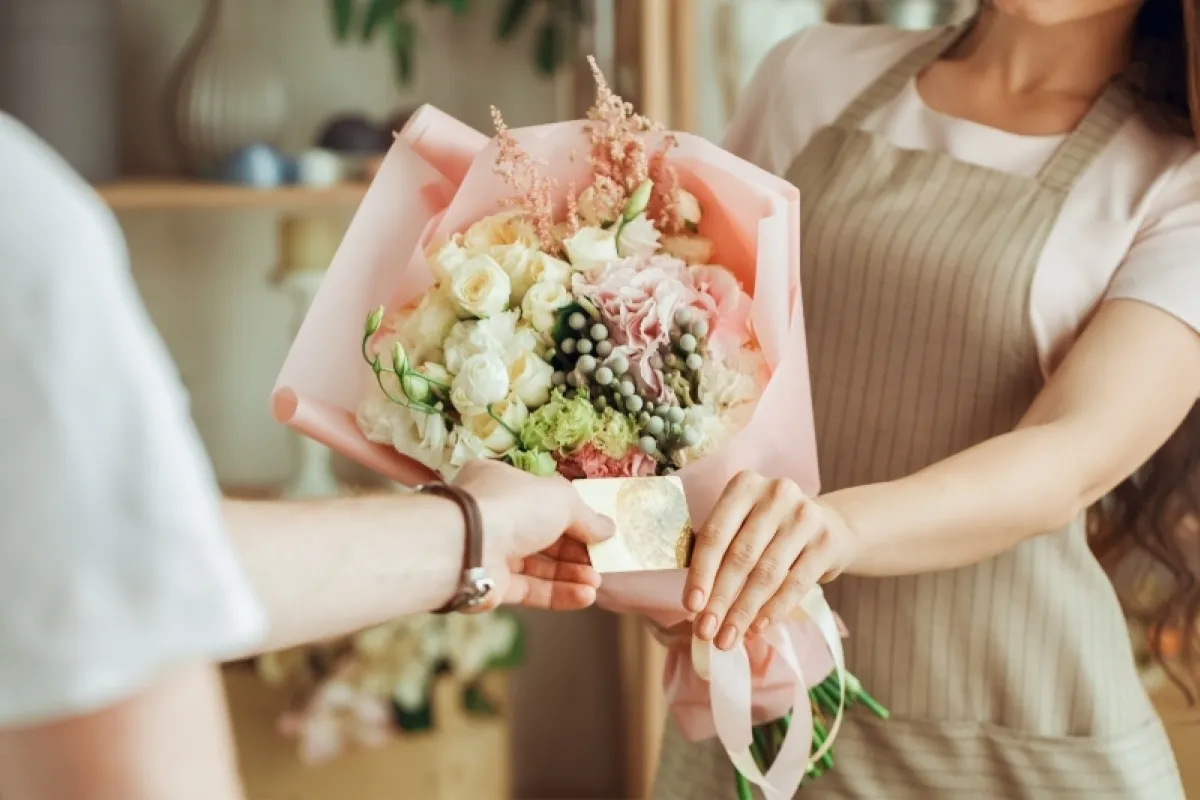 Florist handing a bouquet and card to a returning customer